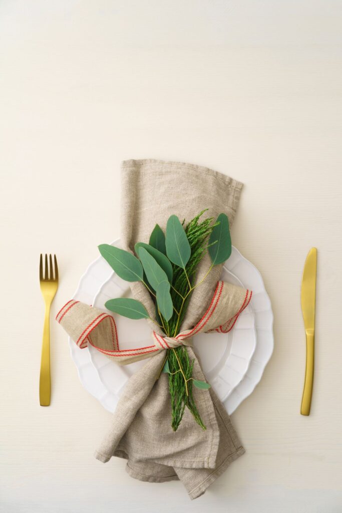 Place setting of white plates with a natural linen napkins and gold cutlery.