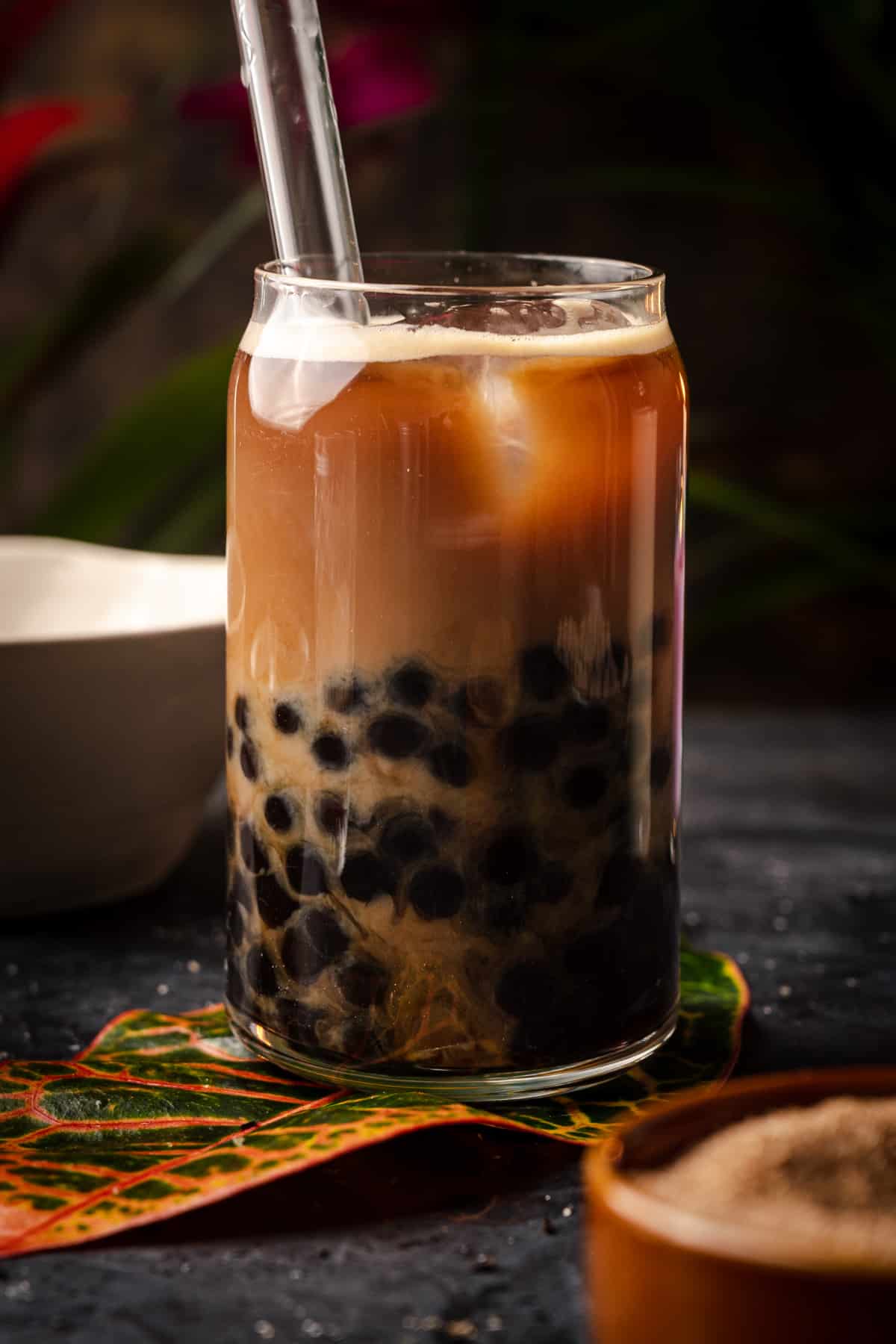 Close up of coffee milk tea with a glass bubble tea straw.