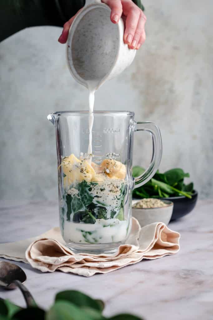 Ingredients for pineapple spinach smoothie in a glass blender.