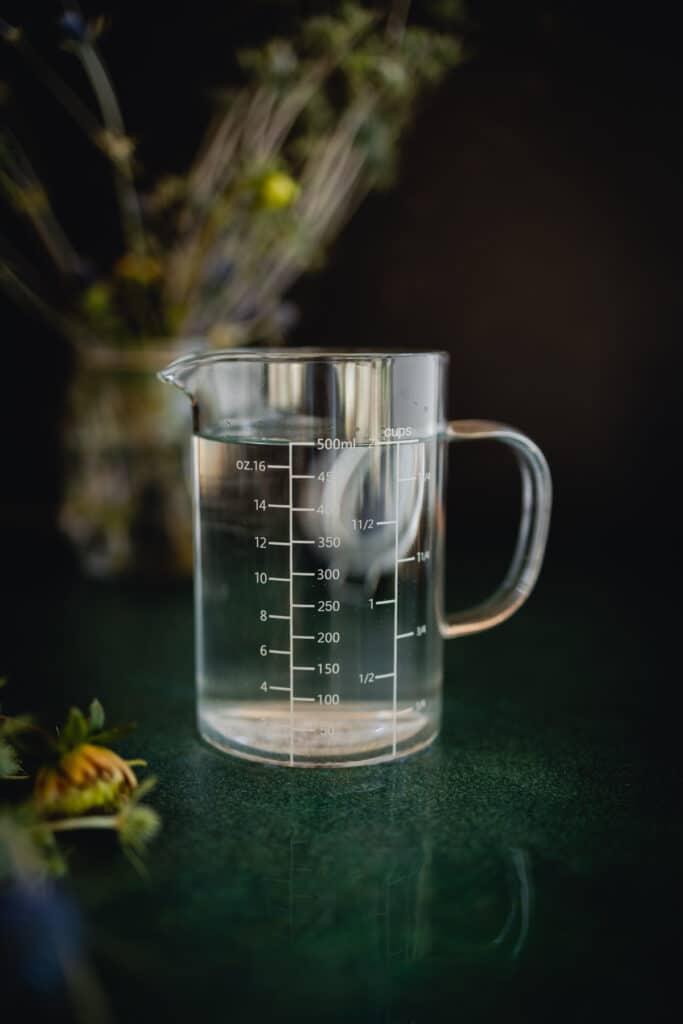 Glass half liter measuring caraf on a green counter.