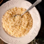 Close up of cooked orzo in a white bowl.