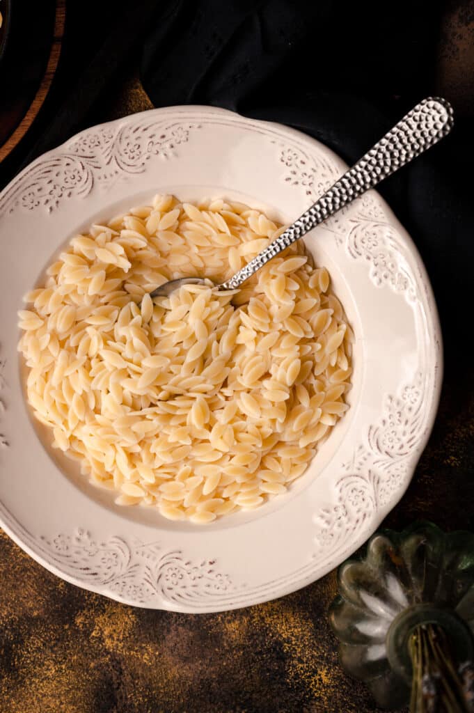 Close up of cooked orzo in a white bowl.