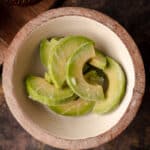Wooden bowl filled with frozen avocado slices.