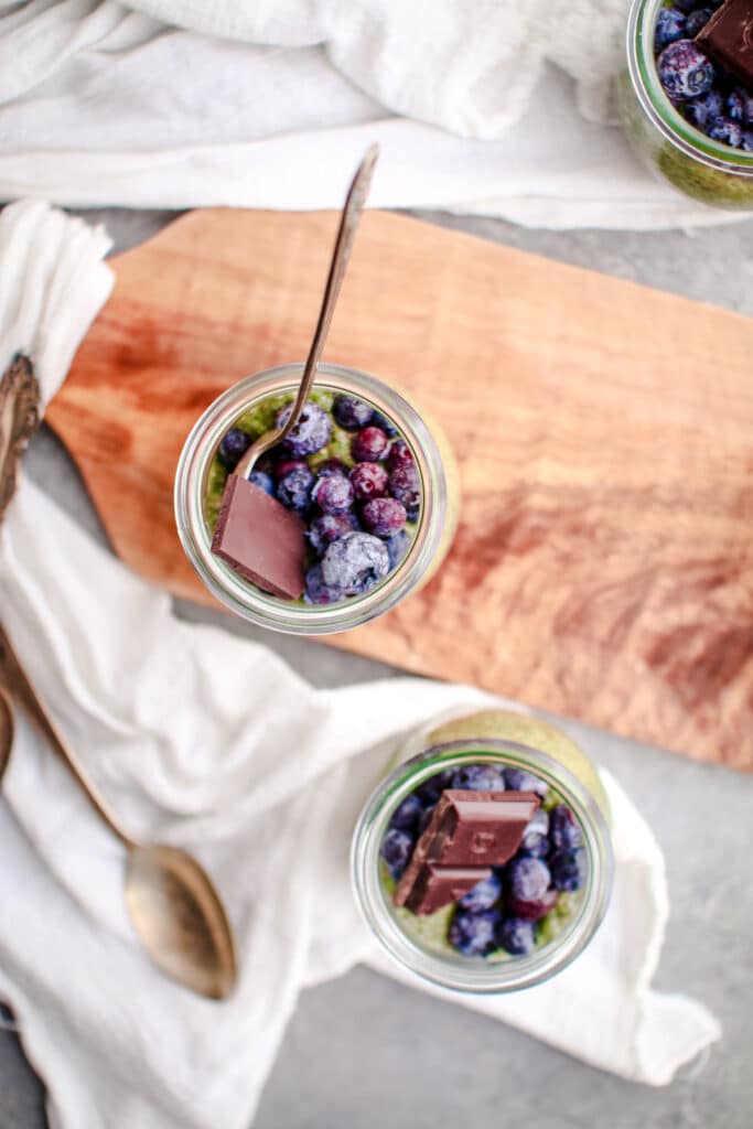 Matcha chia seed pudding topped with fresh blueberries and chocolate.