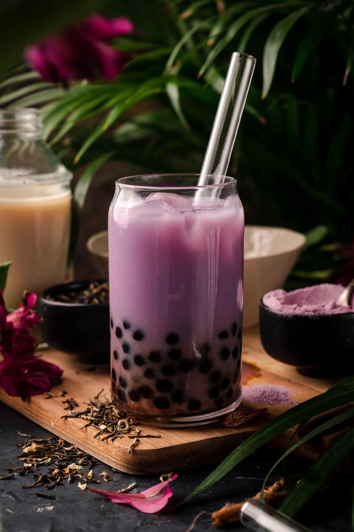Vibrant purple taro bubble tea in a clear cup with fresh boba and a glass straw.