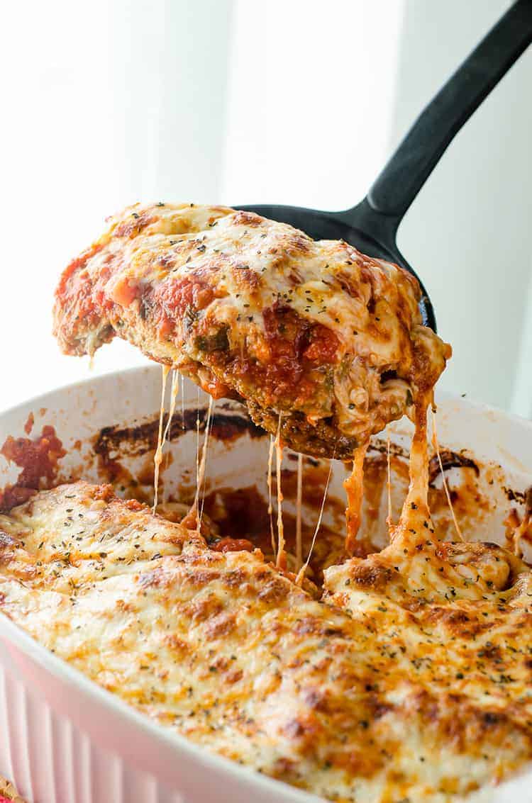 A lasagna being lifted out of a casserole dish.
