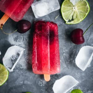 Popsicles with cherry, lime and ice cubes.