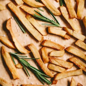 French fries on a baking sheet with rosemary sprigs.