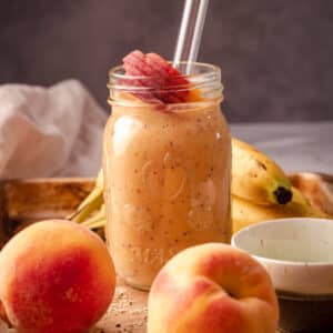 Peach smoothie in a mason jar with bananas and peaches.