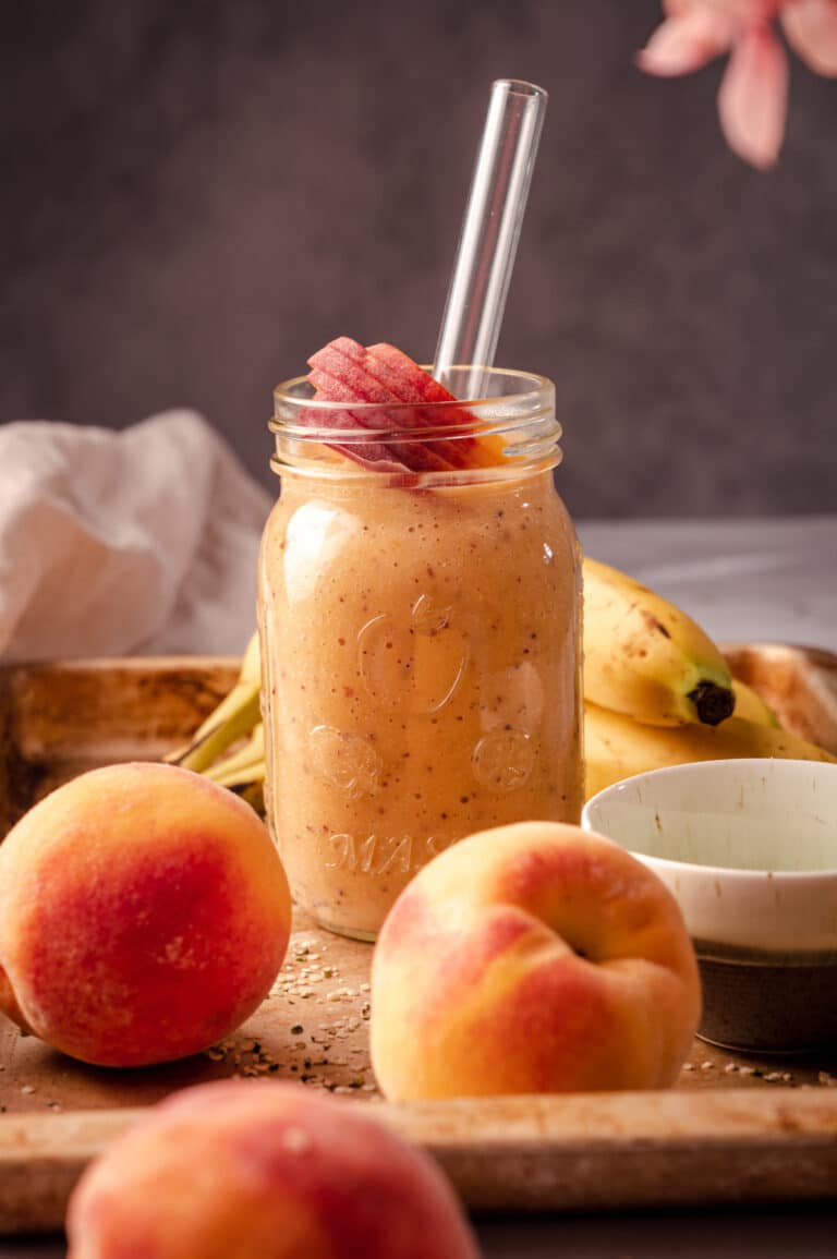 Peach smoothie in a mason jar with bananas and peaches.