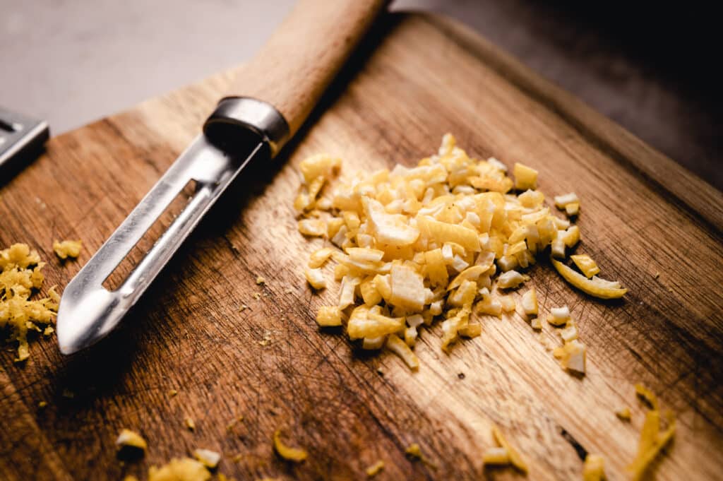 A knife on a cutting board next to some chopped garlic.