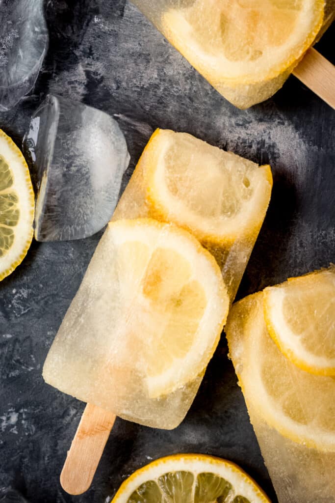 A popsicle with lemon slices on a black surface.