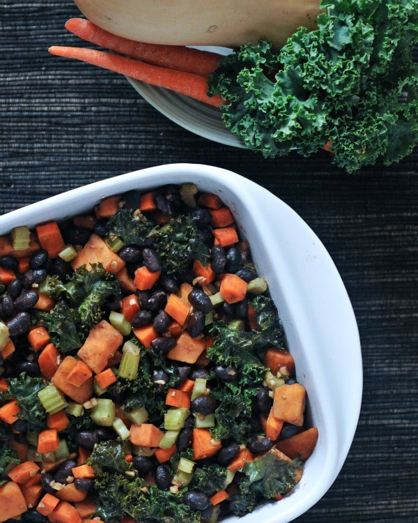A white dish with black beans, kale, and brussels sprouts.