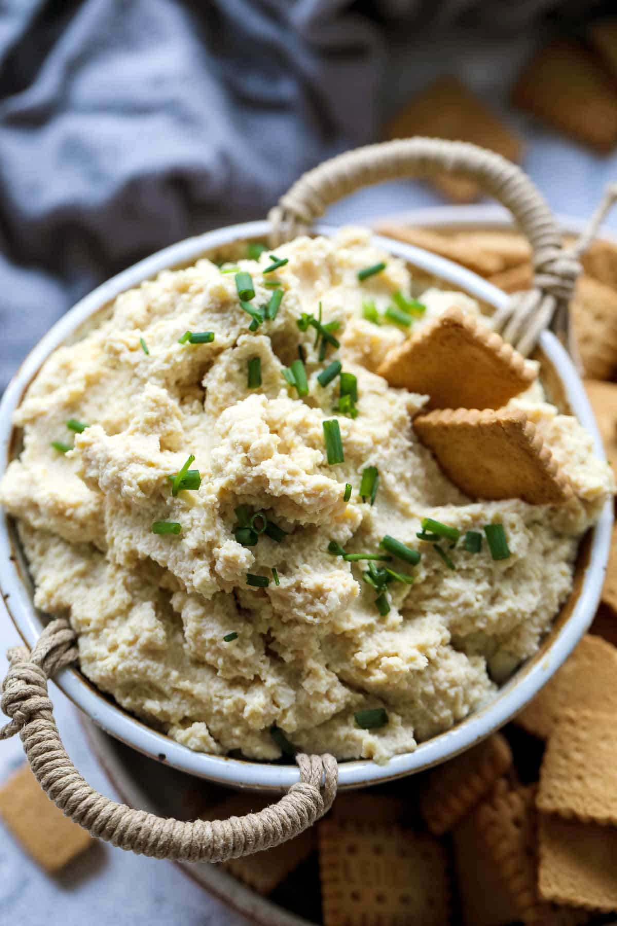 A bowl of dip with crackers and crackers.