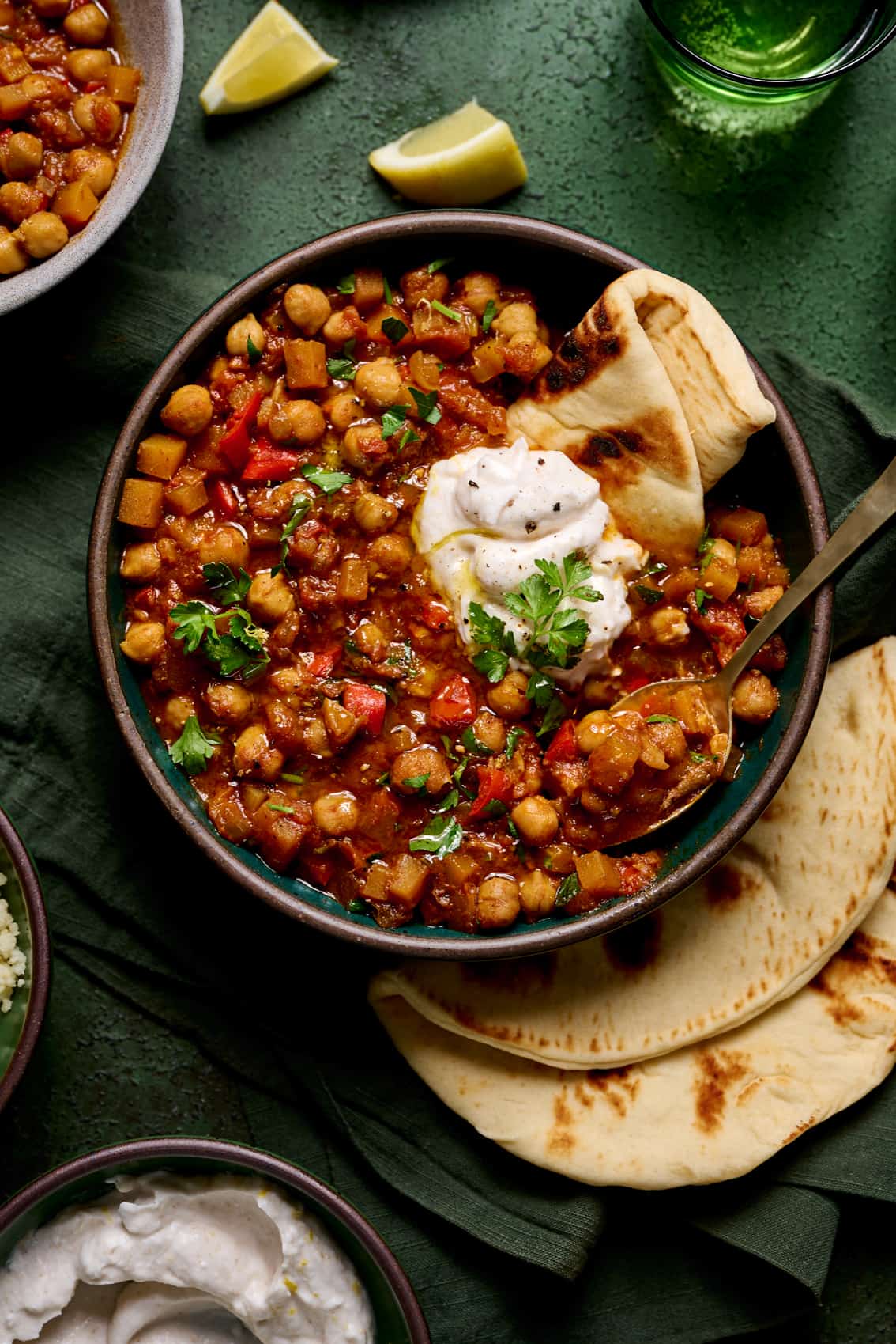A bowl of chickpea stew with tzatziki sauce and pita bread.
