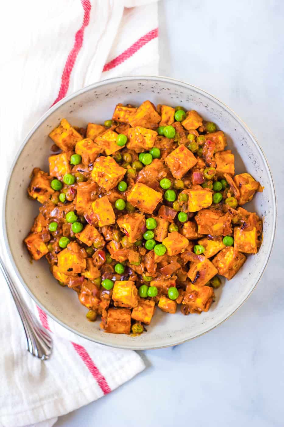 A bowl of sweet potato and peas with a fork.