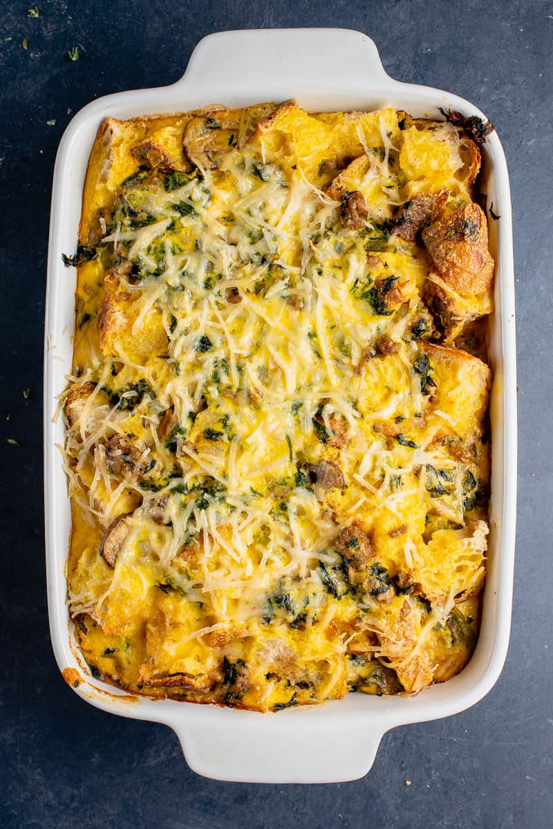 A casserole dish filled with cheesy spinach and mushroom casserole.
