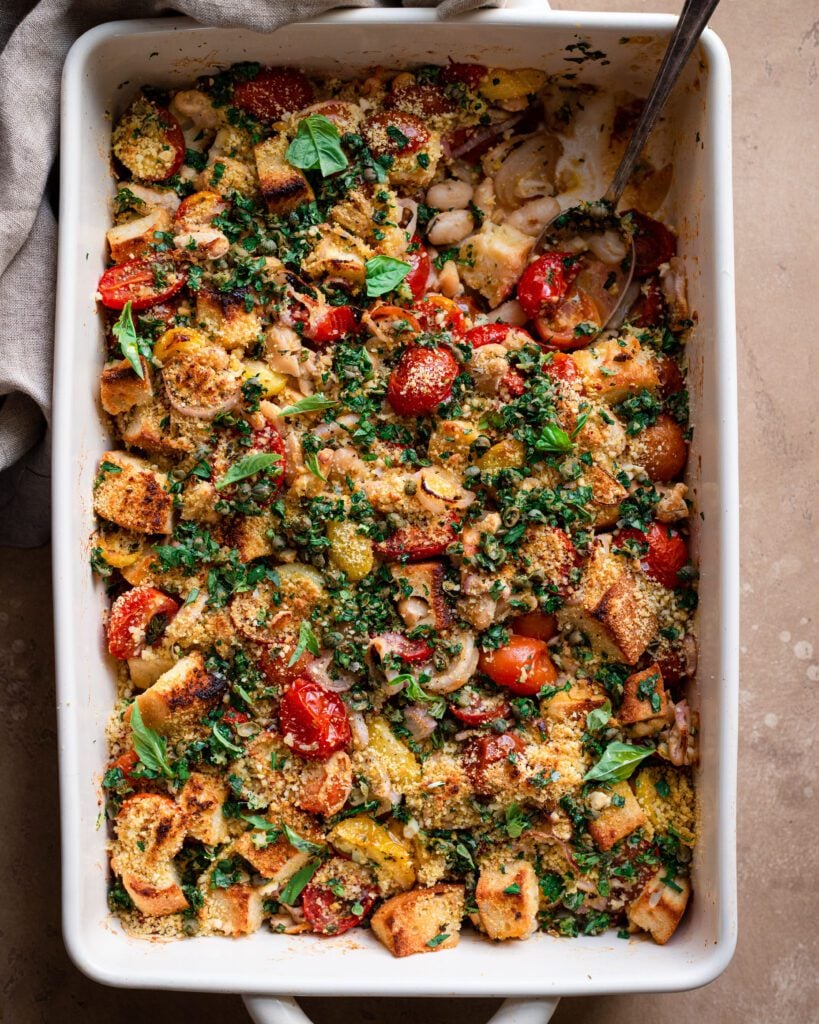 A casserole dish with tomatoes, spinach and breadcrumbs.