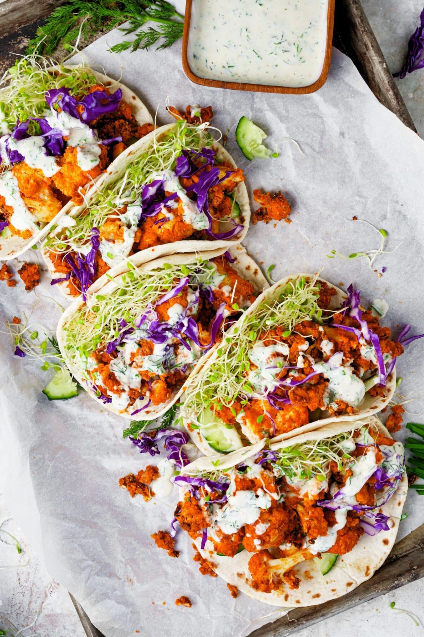 A tray of tacos with slaw and sauce on it.