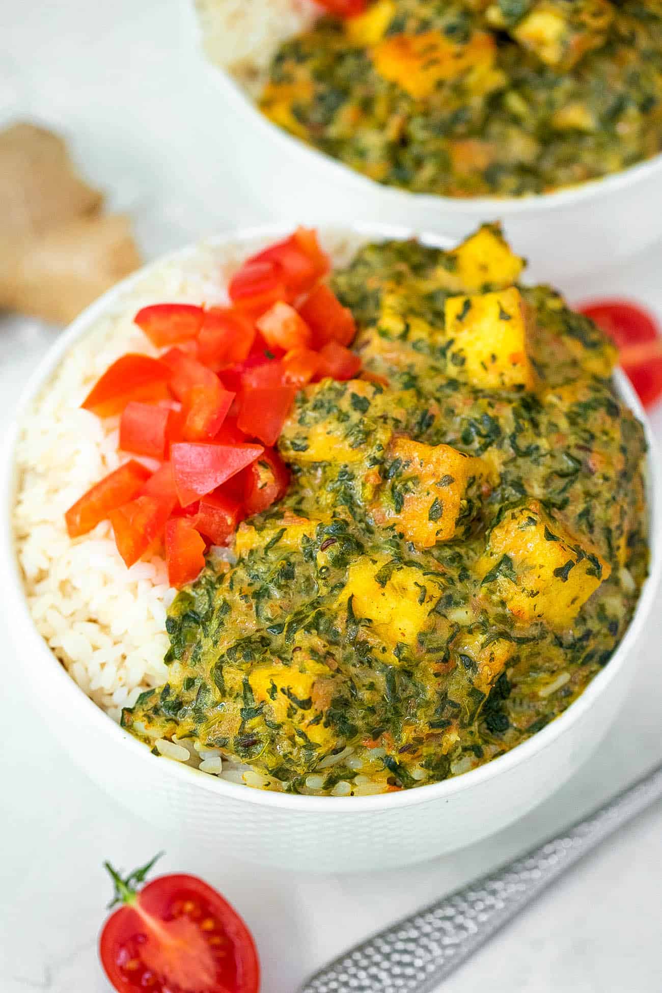 Two bowls of rice with spinach and tomatoes.
