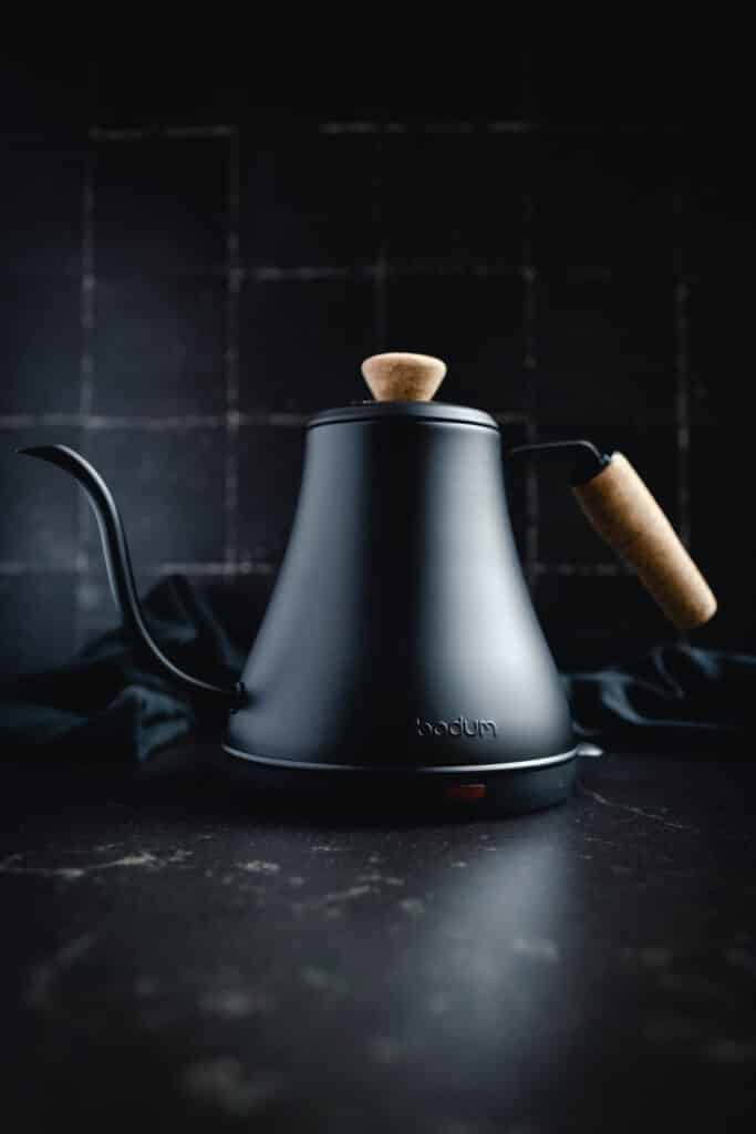 A black kettle with a wooden handle on it.