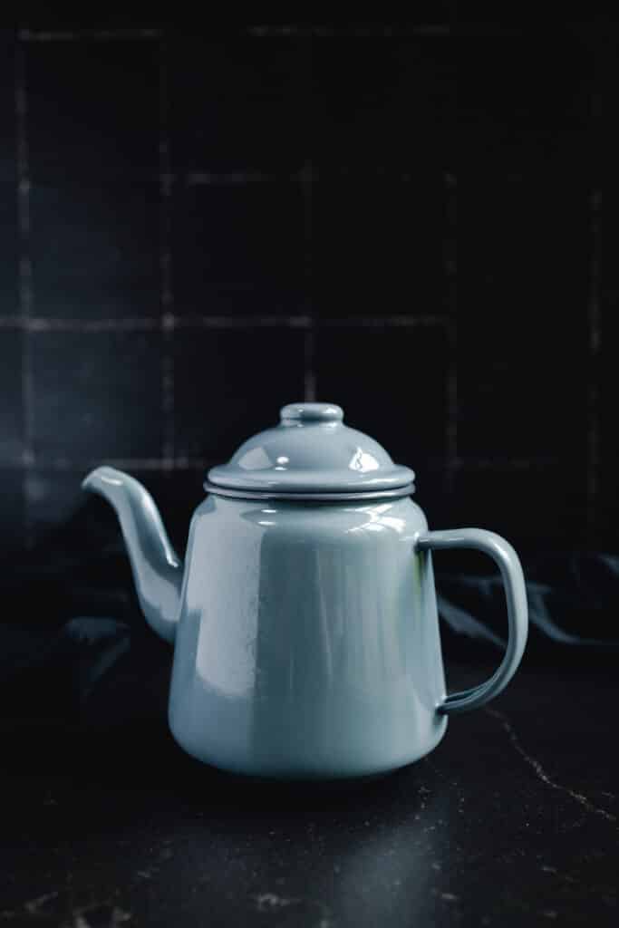 A blue teapot sitting on a black table.
