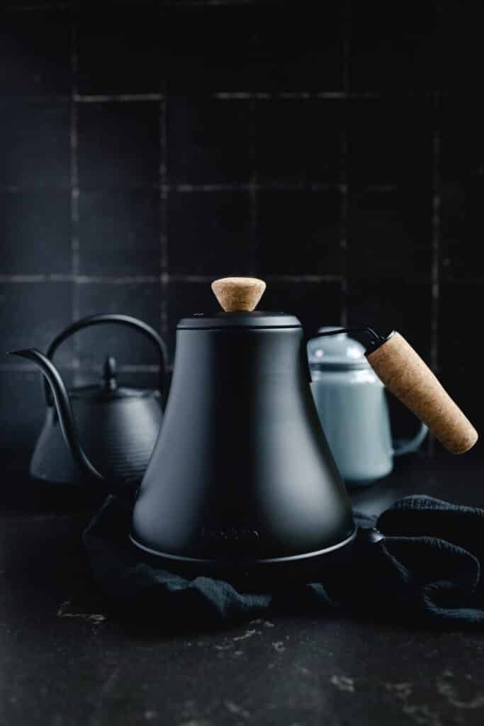 A black tea kettle with a wooden handle.