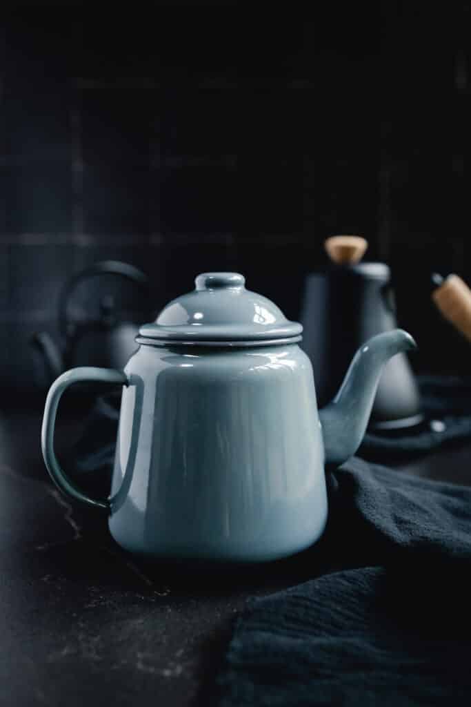 A blue teapot sits on a black table.