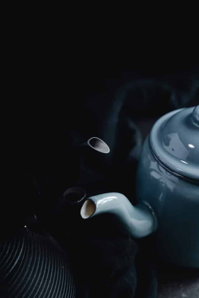A blue teapot on a black background.