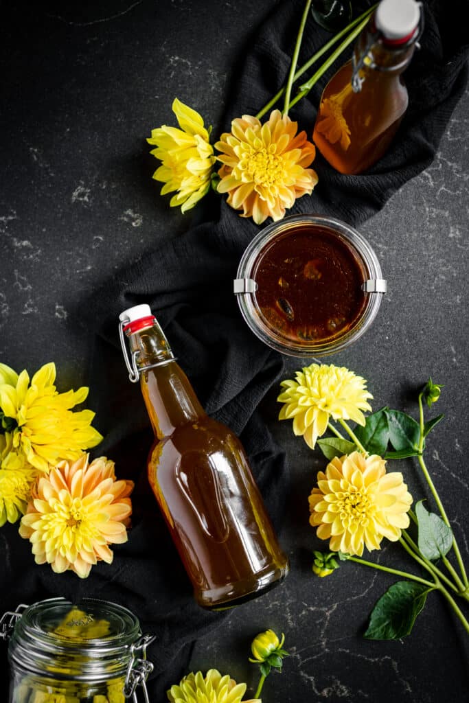 A bottle of honey and flowers on a black background.