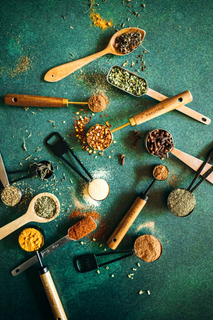 Various spices and spoons on a green background.