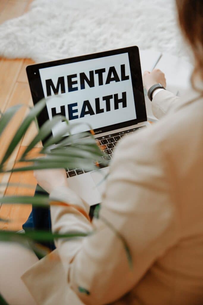 A woman using a laptop with the word mental health on it.