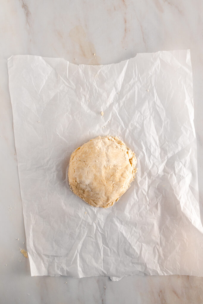 A vegan pie crust made with coconut oil placed on a piece of paper.