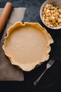 A pie crust with apples and a rolling pin.