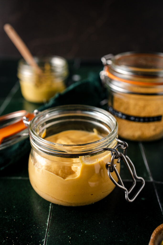 A jar of mustard with a spoon next to it.