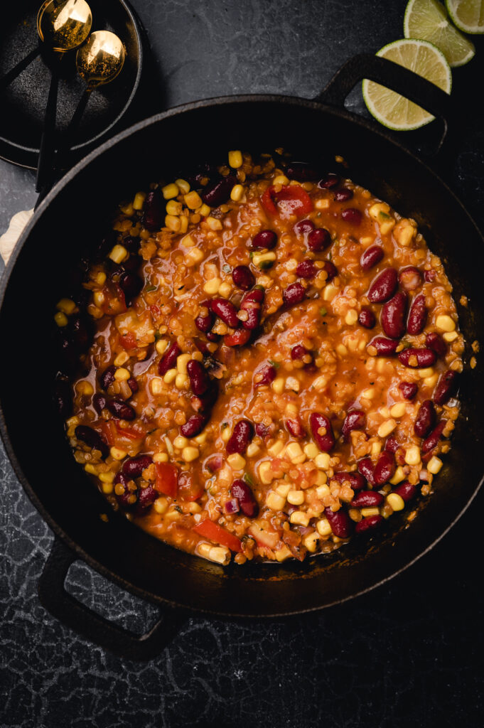 A pot of chili with beans and corn on a table.
