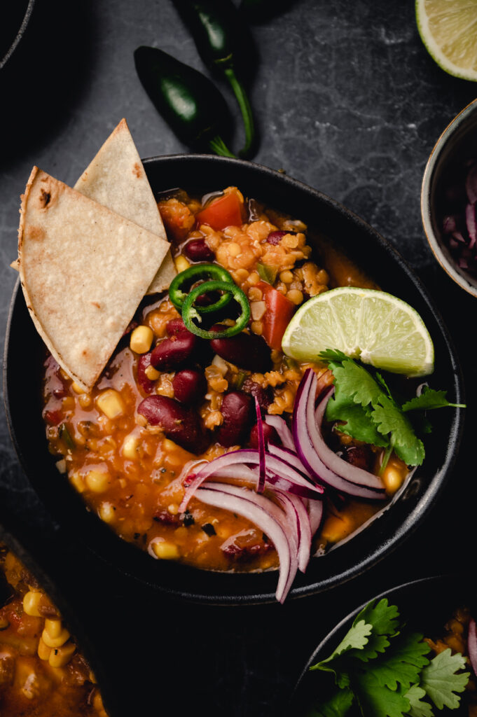 Hearty bowl of vegan chili with tasty toppings.