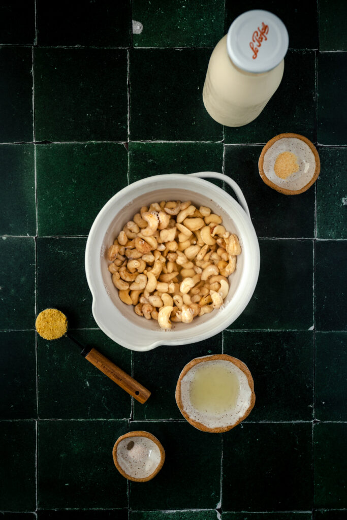 Cashews soaking in water in a white ceramic bowl.