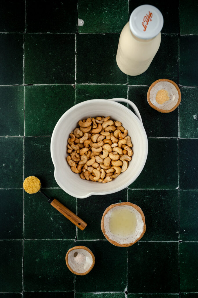 A bowl of nuts and a bottle of milk on a green tiled countertop.