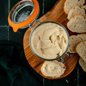 Fresh cashew ricotta cheese in a glass jar with slices of bread.