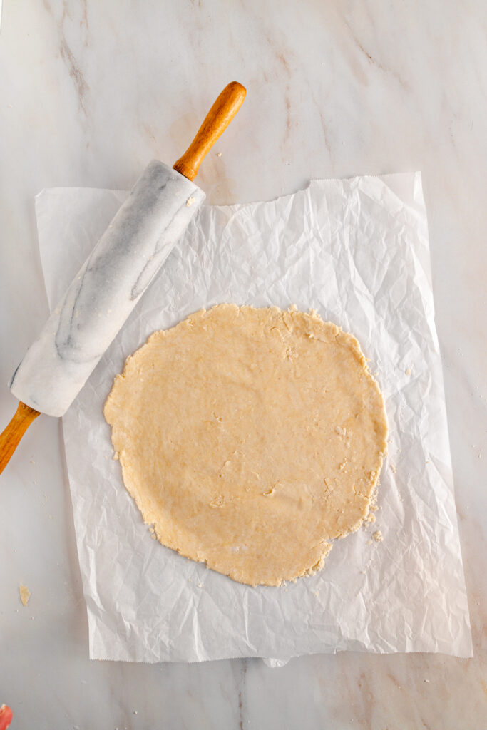 A rolling pin on a piece of paper next to a dough.