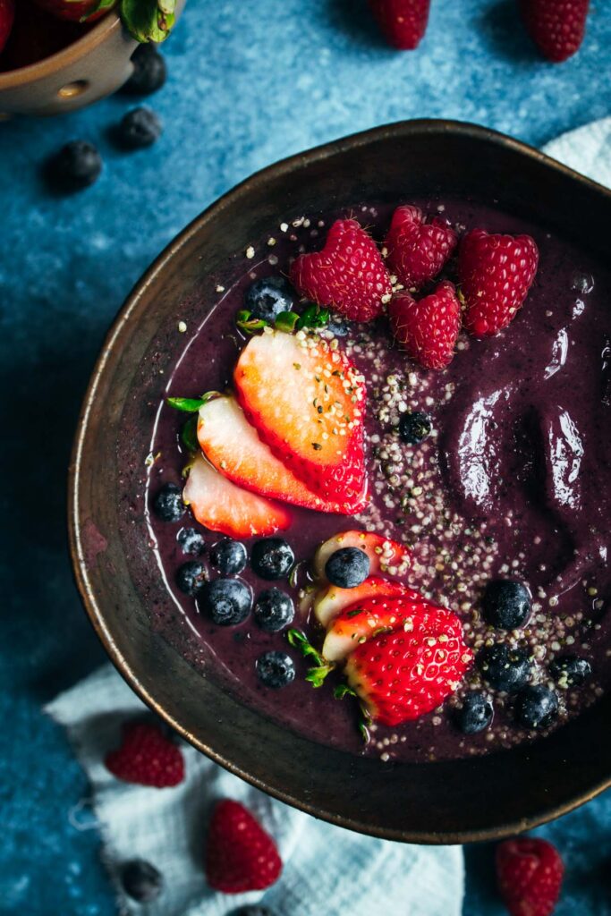 A bowl of smoothie with strawberries and blueberries.