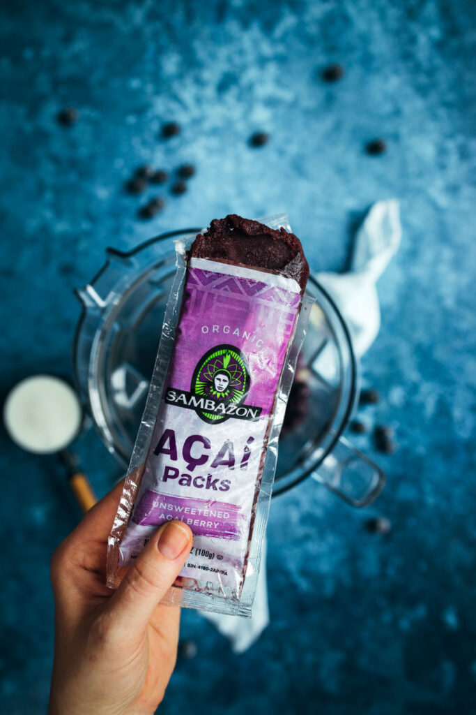 A hand holding a a package of acai puree bar.