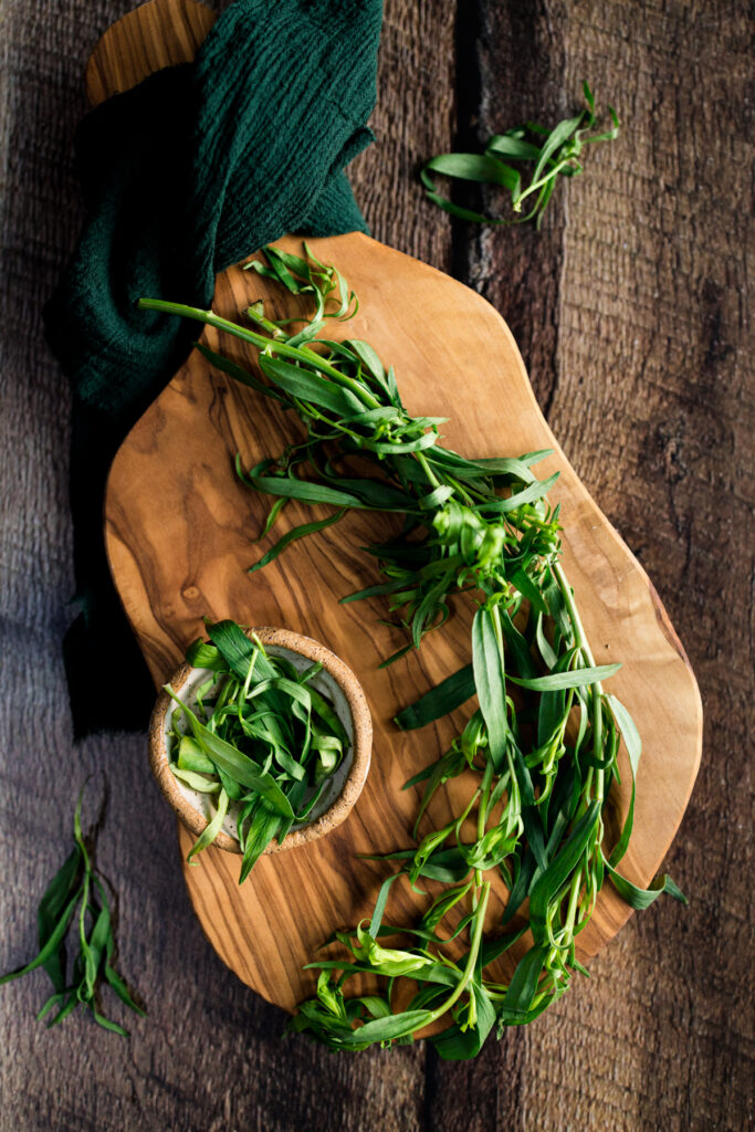 A wooden cutting board with herbs on it.