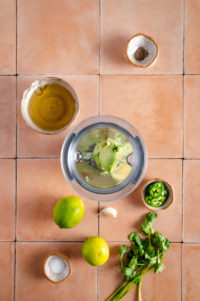 A bowl with limes, lemons and other ingredients on a tiled floor.