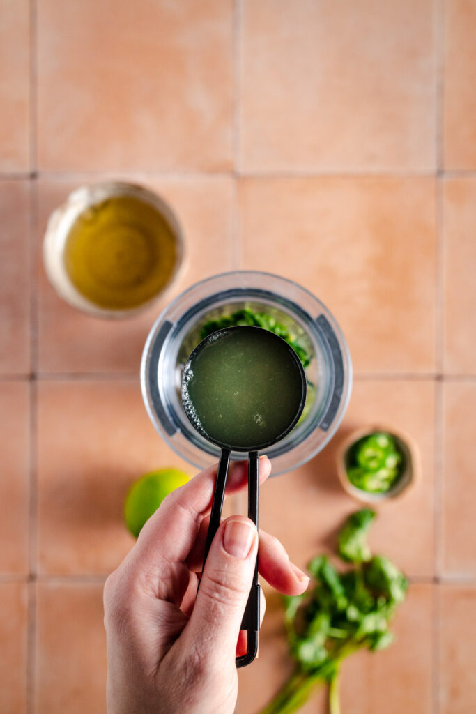 A person is holding a bowl of green sauce.