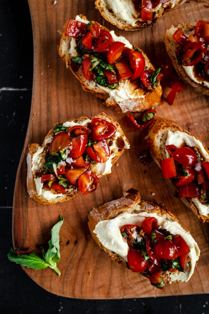 Bruschetta with tomatoes and basil on a wooden cutting board.