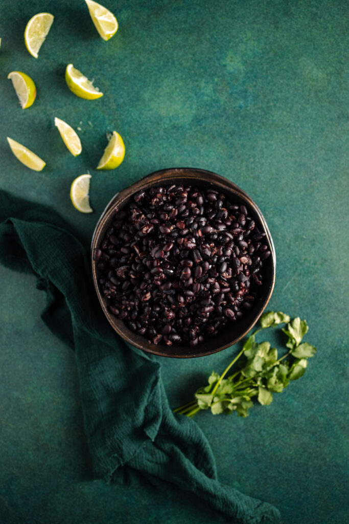 Black beans in a bowl on a green background.