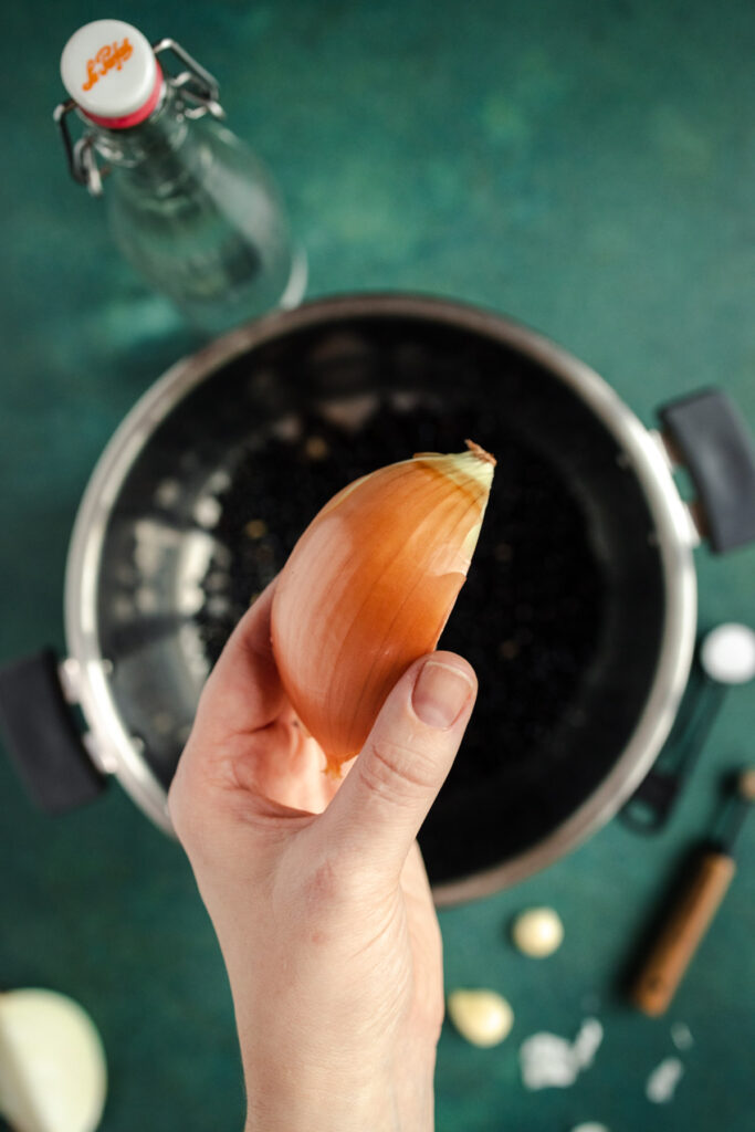 A person holding an onion in a pot.