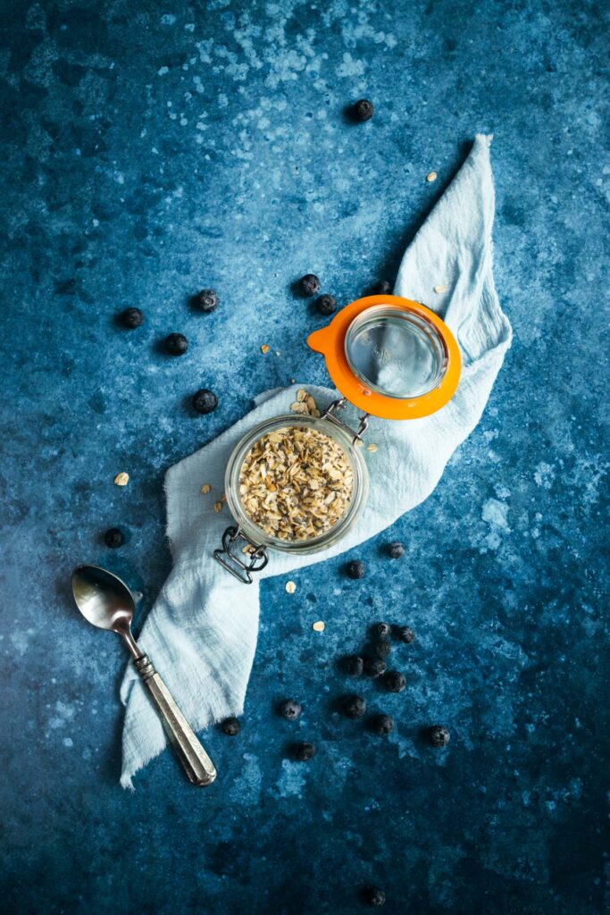A jar of oats and a spoon on a blue background.